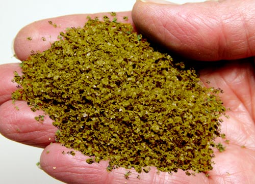 Scenic Express Moss Green SuperLeaf material in a hand, showing its color and loose leaf-flake texture