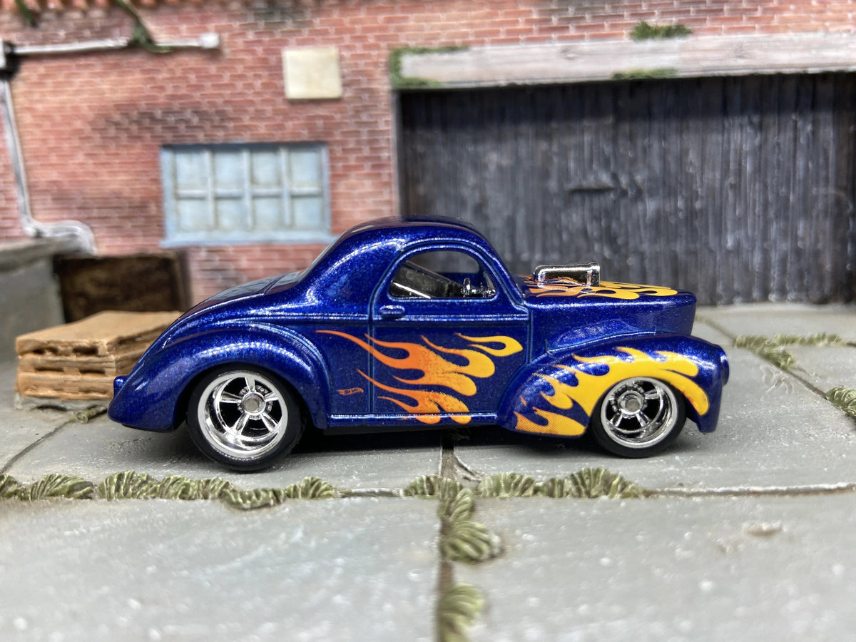 Hot rod Hot Wheels azul con llamas amarillas y naranjas, rines plateados y neumáticos negros