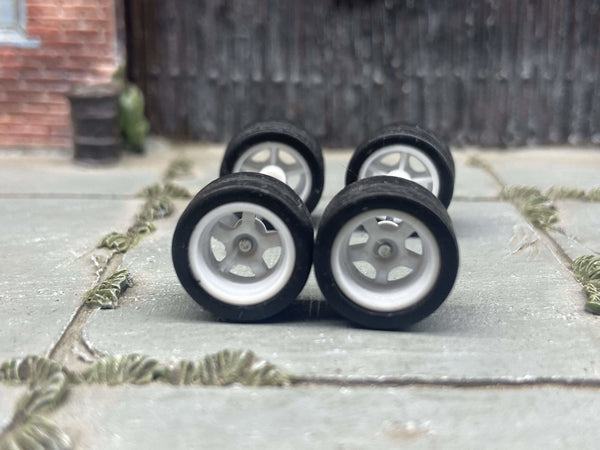 Four white 5-spoke deep-dish wheels with fitted black rubber tires