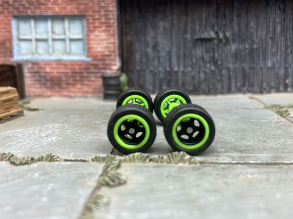Front view of four 12mm black-and-green racing 5-spoke wheels with black rubber tires