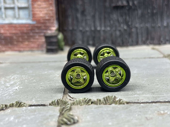 Front view of four 10mm green anodized 5-star wheels with black rubber tires