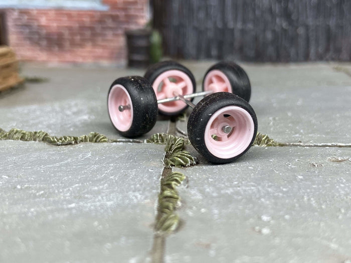 Close-up of four pink four-spoke wheels with black tires