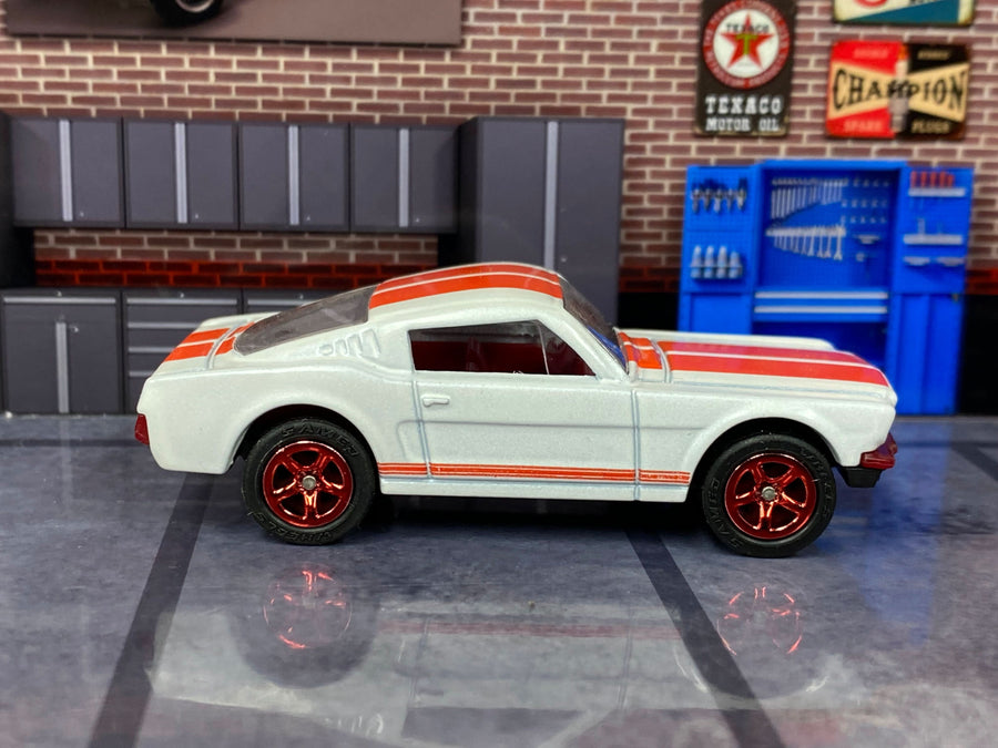 Pearl-white 1965 Mustang GT custom Matchbox with raised-letter rubber tires and red five-spoke wheels