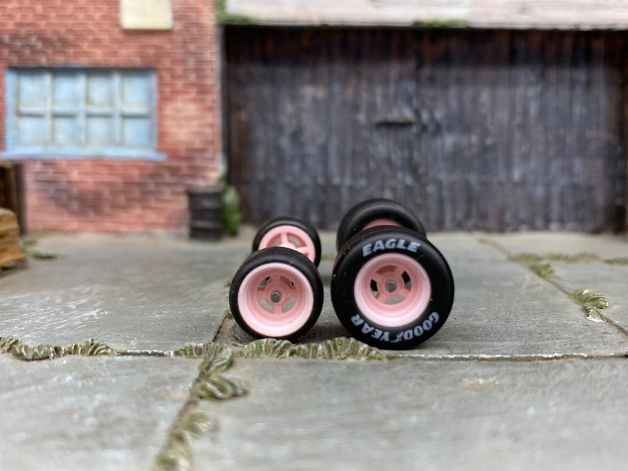 Pink four-spoke staggered replacement wheels with rubber tires for a custom diecast project