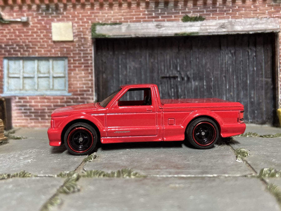 Red custom Hot Wheels GMC Syclone with black wheels and red wheel accents