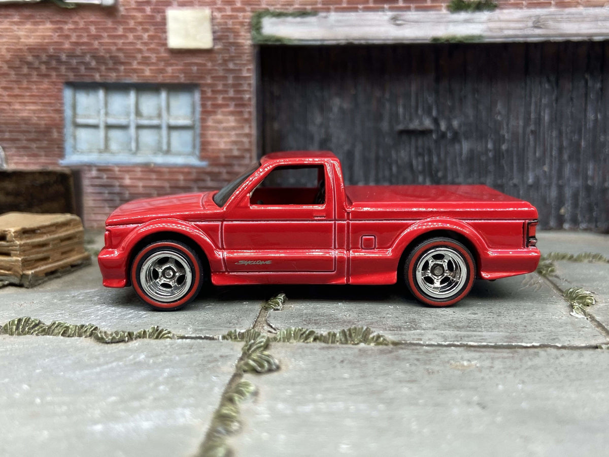 Red custom Hot Wheels GMC Syclone with chrome wheels and redline tires, viewed from the side