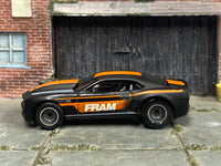 Satin-black 2013 COPO Camaro with orange FRAM side graphics, left-side view