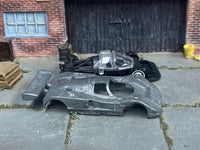 Stripped Mazda 787B race-car body beside its matching donor assembly