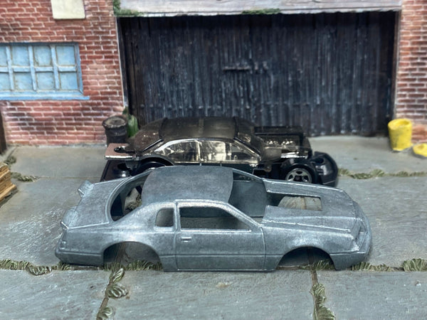 Stripped 1986 Ford Thunderbird Pro Stock body beside its matching donor assembly