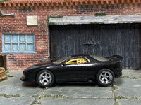 Metallic black custom Pontiac Firebird with chrome wheels, left-side view