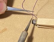 Manufacturer demonstration of soldering wires to a Mini Cube 3 speaker; wire and tools are not included