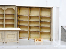 Banta Modelworks 704 O scale three-wide shelf unit kit, assembled unit identified by the 704 label; surrounding furniture is separate.
