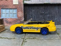 Custom Hot Wheels 1996 Mustang GT Convertible in yellow and blue Butterfinger livery with blue mag wheels and rubber tires