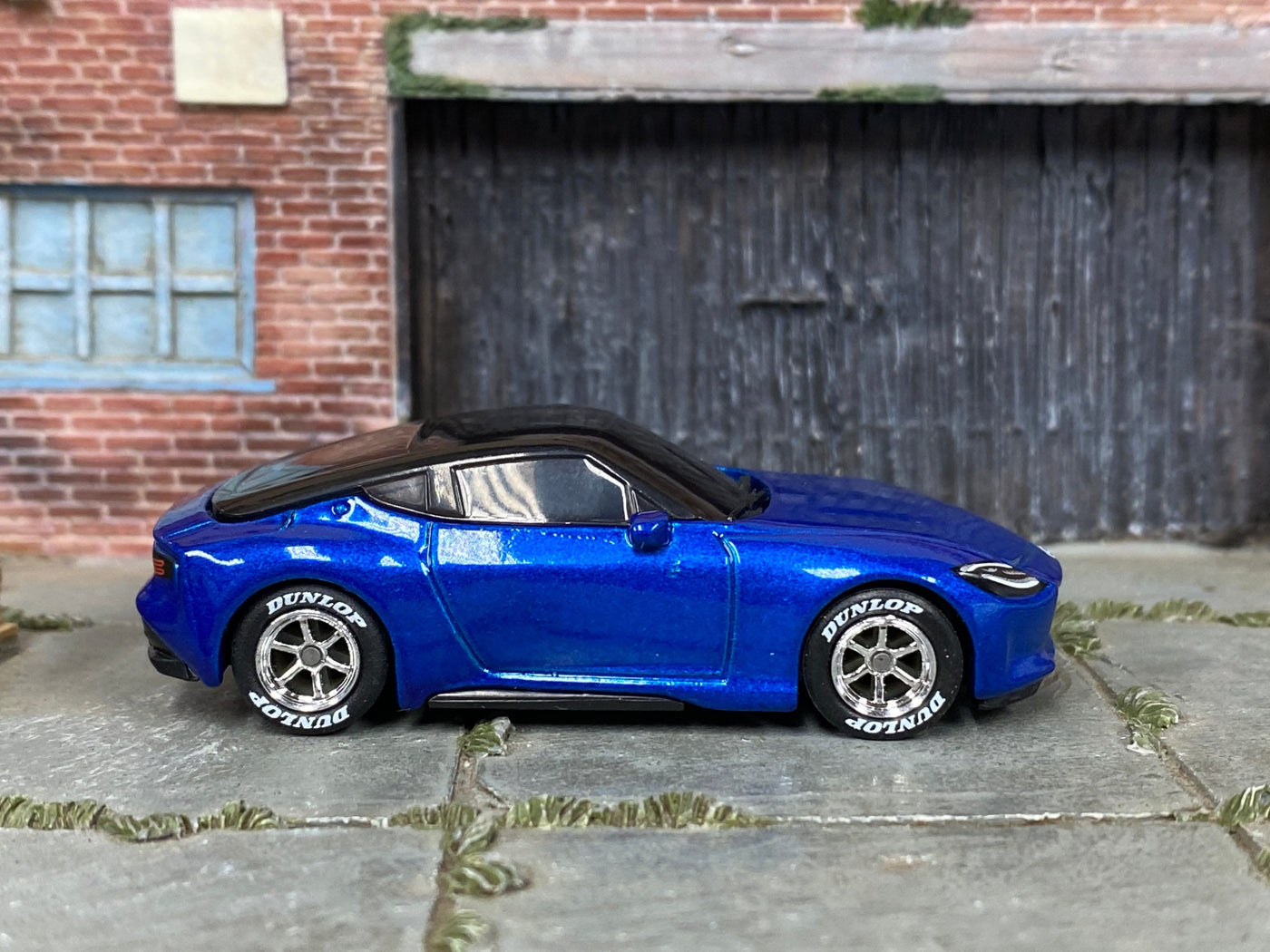 Right-side view of metallic-blue custom Hot Wheels 2023 Nissan Z with chrome wheels and Dunlop tires