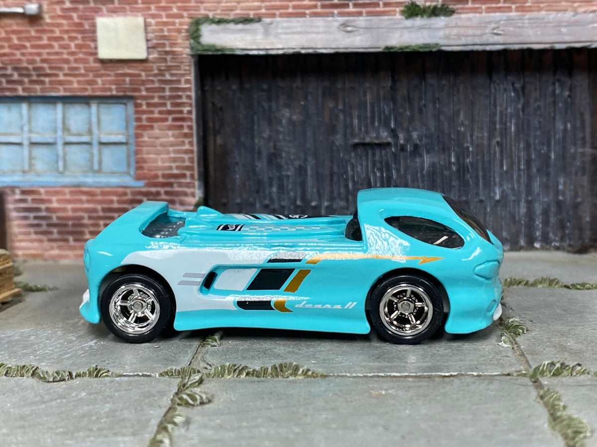 Custom Hot Wheels Deora II aqua blue with white, black, and gold graphics with chrome wheels and rubber tires - side view