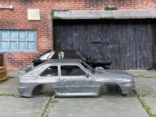 Stripped bare-metal 1984 Audi Sport Quattro body beside matching kit components