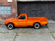 Hot Wheels Datsun 620 orange with yellow stripes and Bridgestone graphics, left side view