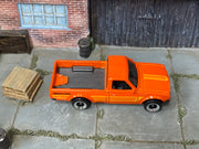 Hot Wheels Datsun 620 orange with yellow stripes and Bridgestone graphics, top view