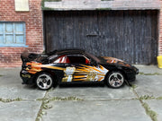 Hot Wheels Saleen S7 black with orange and gold fist graphics left-side view