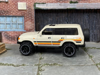 Hot Wheels Toyota Land Cruiser 80 2023 white with orange stripes, left-side view