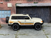 Hot Wheels Toyota Land Cruiser 80 2023 white with orange stripes, right-side view