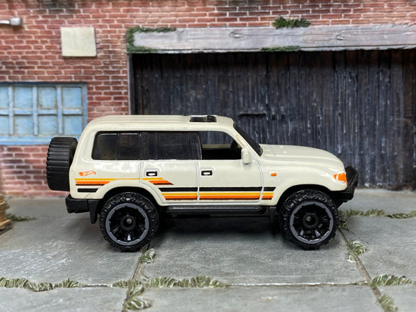 Hot Wheels Toyota Land Cruiser 80 2023 white with orange stripes, right-side view