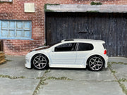 Hot Wheels Volkswagen Golf GTI pearl white with black hood, left-side view
