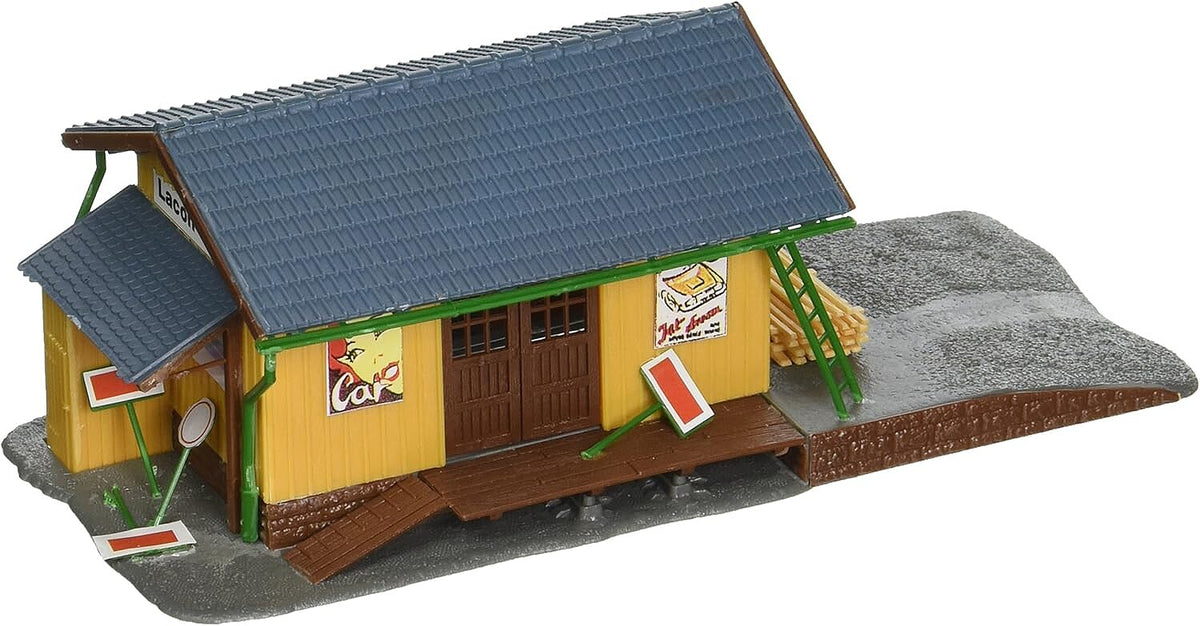 Model Power 694 HO scale Farmingdale Freight Station, assembled building with yellow walls, gray roof and loading platform; three-quarter product view.
