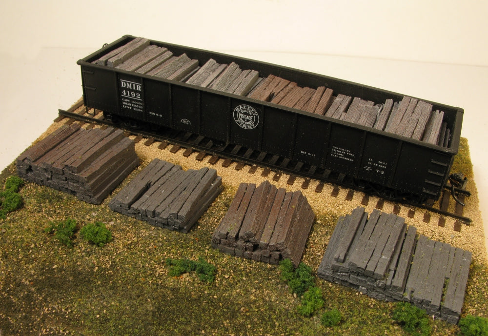 Monroe Models 2108 HO scale weathered railroad tie stacks, four-pack. Manufacturer example shows four painted stacks in front and four arranged as a gondola load; railcar, track and scenery are not included.