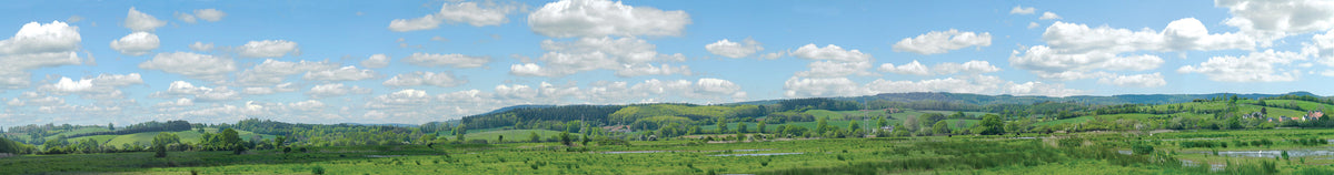 PECO SK-P05 Water Meadow photographic backscene showing green fields, water, distant hills and a cloudy blue sky.