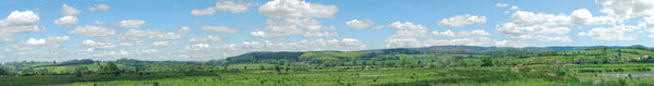 PECO SK-P05 Water Meadow photographic backscene showing green fields, water, distant hills and a cloudy blue sky.