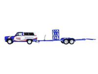 Side view of the blue-and-white Hendrick K5 Blazer towing an empty tandem car trailer with ramps extended, GreenLight 1:64.