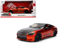 Orange metallic 2023 Nissan Z with dark hood and black roof, beside JDM Tuners packaging, Jada 37490