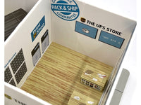 Overhead view inside The UPS Store diorama showing printed wall signs, wood-pattern flooring and counter details; GreenLight 51491.