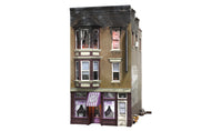 Woodland Scenics BR5051 Betty's Burning Building HO scale Built-&-Ready model, front view with scorched upper floor and purple shop awning.