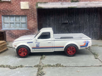 Rear three-quarter view of white-and-red Datsun 620 with rubber tires