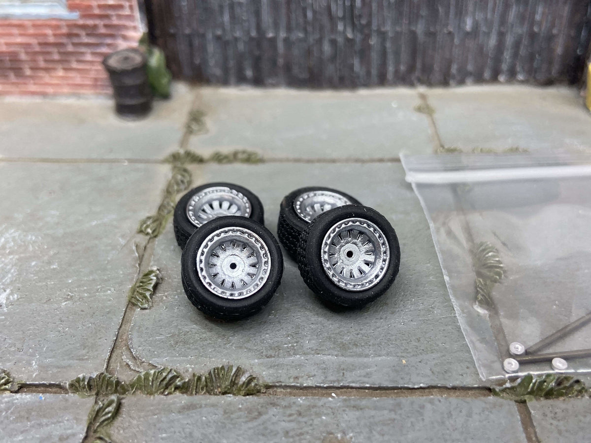 Four 12mm silver AR-style wheels with black rubber tires, view 1