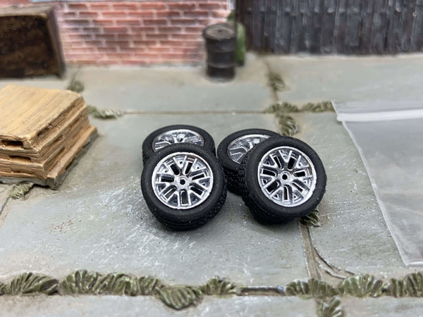 Four 12mm silver FR500-style wheels with black rubber tires, view 1