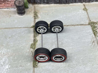 Overhead view of chrome deep-dish wheels with red-line tires on two axle rods