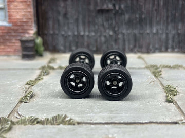 Front view of four black five-spoke deep-dish wheels with rubber tires