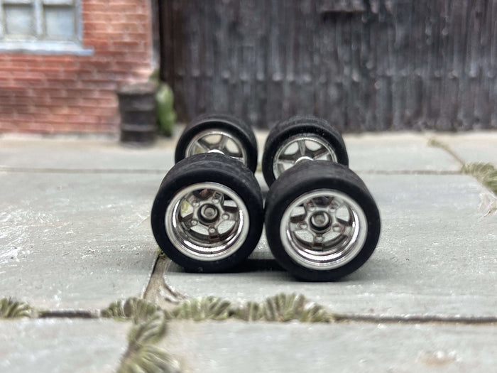 Front view of four chrome five-spoke deep-dish wheels with black rubber tires