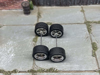 Overhead view of chrome deep-dish wheels on two axle rods, showing tire tread and rear hubs