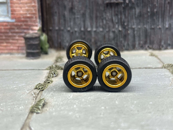 Front view of four 10mm gold 5-spoke deep-dish wheels with black rubber tires