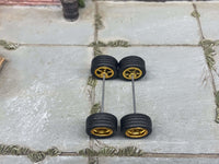 Overhead view of four gold deep-dish wheels with black rubber tires positioned on axle rods