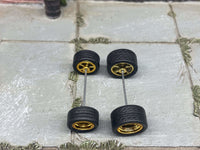 Overhead view of staggered gold deep-dish wheels with black rubber tires positioned on axle rods
