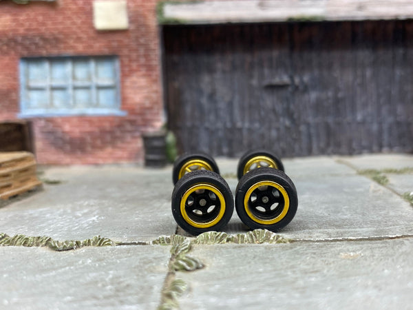 Front view of four black-and-gold 5-spoke wheels with black rubber tires