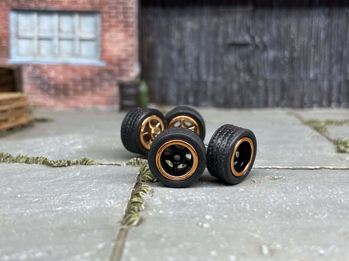 Four black-and-gold 5-spoke wheels with fitted black rubber tires