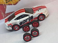 Overhead view of four chrome and red-lip wheels on axles beside a display car