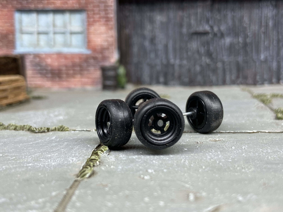Close-up of four black four-spoke wheels with black tires