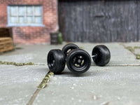 Close-up of four black four-spoke wheels with black tires
